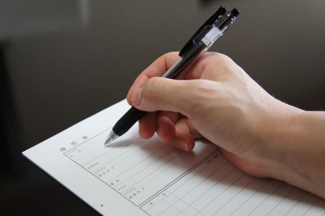 丁寧に履歴書を記入している手元